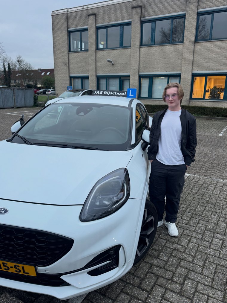 Geslaagde leerling met duim omhoog bij de lesauto van JAS-Rijschool