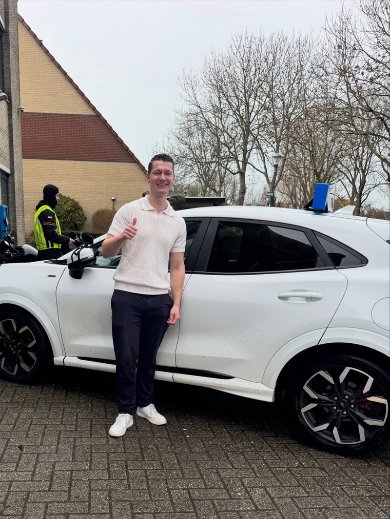Geslaagde leerling trots naast de lesauto van JAS-Rijschool